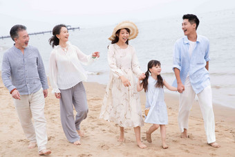 快乐的一家人在海滩上散步白昼高端摄影图