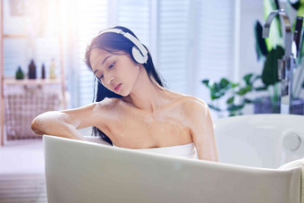 浴缸内听音乐的年轻女孩