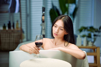 浴缸内漂亮的年轻女人和红酒