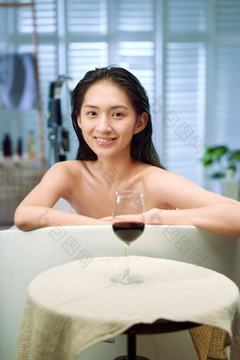 浴缸内漂亮的年轻女人和红酒