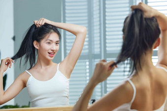 漂亮的年轻女人照着镜子梳头发中国清晰场景