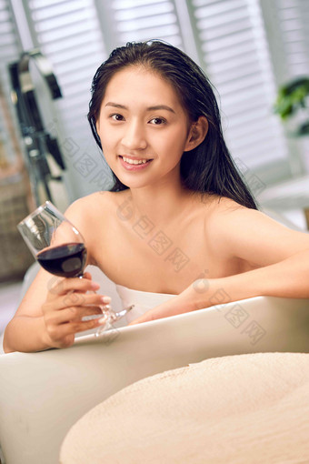 浴缸内漂亮的年轻女人和红酒