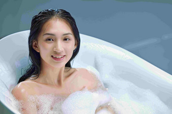 快乐的年轻女人洗泡泡浴热水池浴高端素材