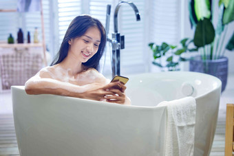 浴缸内使用手机的年轻女孩
