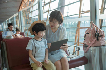 年轻妈妈和儿子在机场候机厅看平板电脑旅途清晰摄影