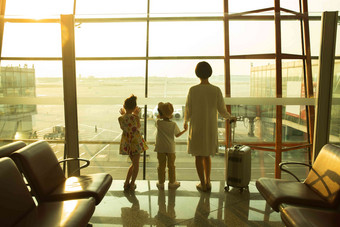 年轻妈妈和孩子在机场候机厅往外看户内写实相片