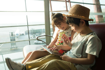 两个小朋友坐在机场<strong>候车厅</strong>看平板电脑旅行者相片