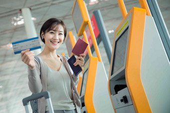 商务女士在机场使用自动售票机拿着高质量相片