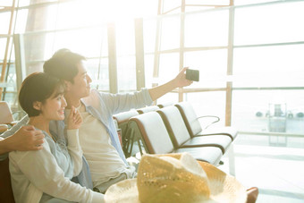 青年情侣坐在机场<strong>候机厅</strong>看手机中国氛围拍摄