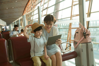 年轻妈妈和儿子在机场候机厅看平板电脑东亚写实照片