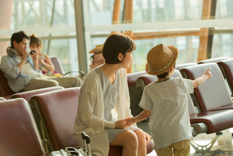 年轻妈妈和儿子在机场候机厅窗户高质量场景
