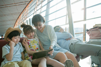 年轻妈妈和孩子们在机场候机厅看平板电脑