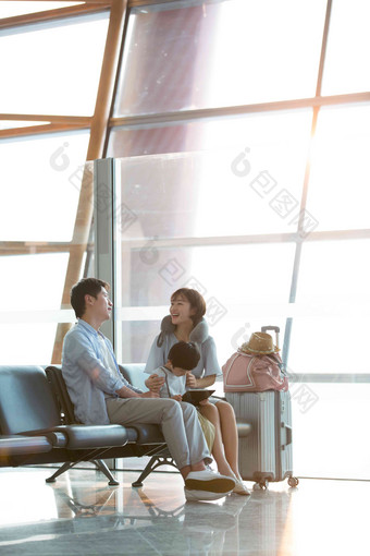 一家三口坐在机场候机大厅候机室写实照片