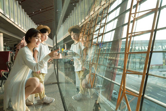 年轻妈妈和儿子从机场候机厅往外看玻璃窗写实图片