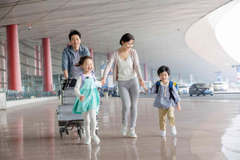 欢乐家庭在机场推着行李四个人场景