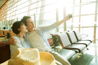 青年情侣坐在机场候机厅看手机