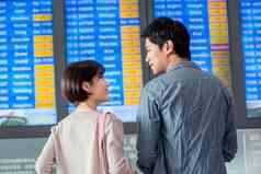 青年情侣在机场候机厅看航班表