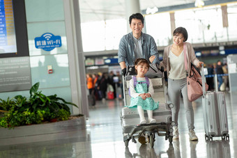 快乐家庭在机场推着行李青年夫妇写实摄影