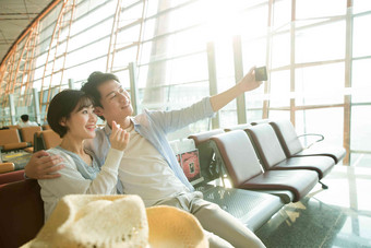 青年情侣坐在机场候机厅看手机大厅氛围摄影
