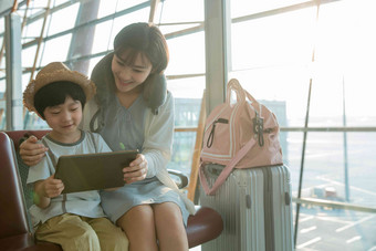 年轻妈妈和儿子在机场候机厅看平板电脑中国清晰摄影