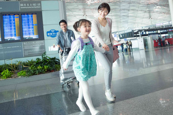 快乐家庭在机场推着行李女孩高质量图片