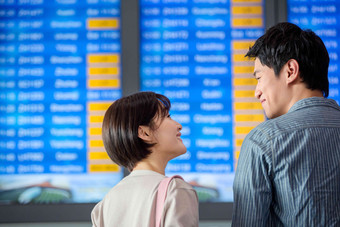 青年情侣在机场候机厅看航班表亚洲人氛围素材