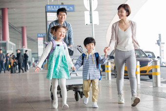 欢乐家庭在机场推着行李旅行者拍摄