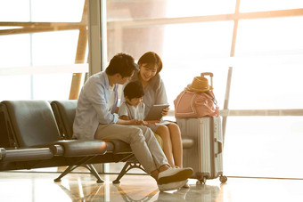 一家三口坐在机场候机大厅行李箱高端镜头