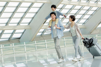 快乐的一家三口在机场步行写实相片