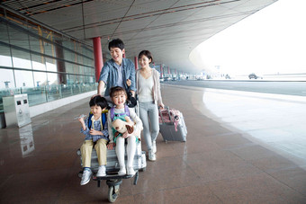 欢乐家庭在机场推着行李人高端图片