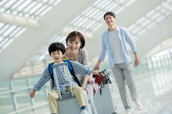 在机场的一家三口快乐旅行嬉戏的高端相片