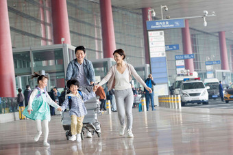 欢乐家庭在机场推着行李人写实相片