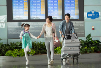 快乐家庭在机场推着行李三个人高清图片