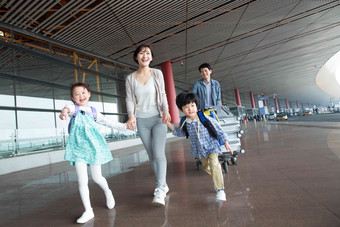 欢乐家庭在机场推着行李四个人高质量图片