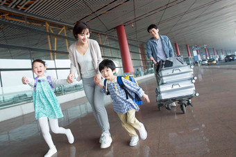 欢乐家庭在机场推着行李人高清图片