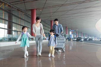 欢乐家庭在机场推着行李步行摄影