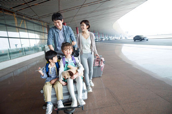 欢乐家庭在机场推着行李户内高质量影相