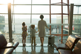 年轻妈妈和孩子在机场候机厅往外看