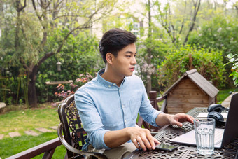 青年男人在院子里用笔记本电脑