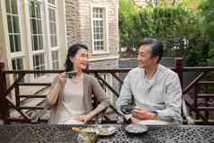 老年夫妇坐在院子里喝茶