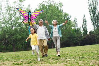 老年夫妇带着孙女在公园里放风筝