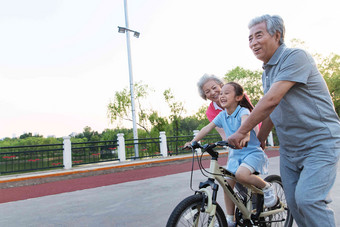老年夫妇带着孙女骑自行车男人写实场景