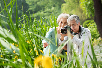 老年夫妇在公园里拍照微笑高清素材