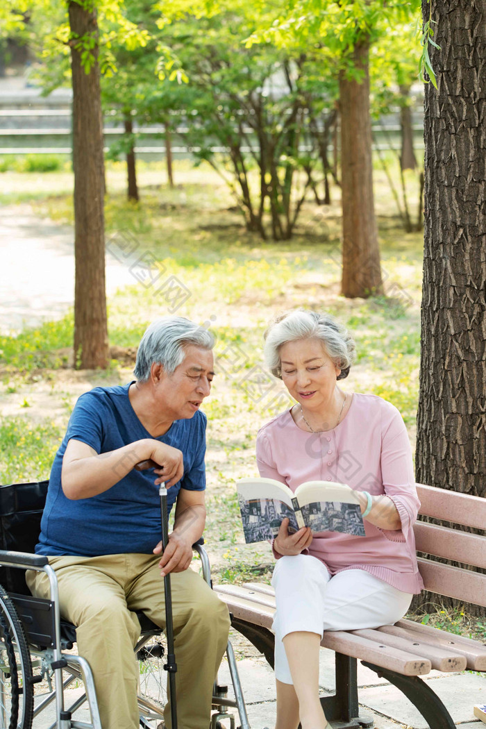 老年夫妇坐在公园里看书休闲装高清素材