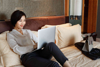 年轻女人坐在床上用电脑