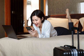 年轻女人趴在床上看手机