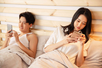 年轻情侣在床上使用手机美丽的摄影图