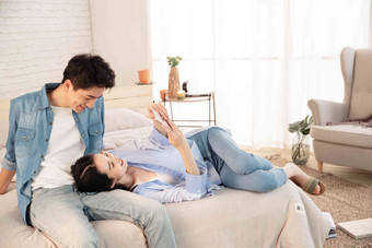 年轻妻子躺在丈夫腿上玩手机放松高质量场景