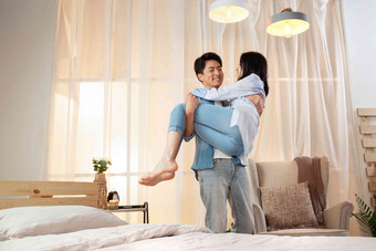 卧室里年轻丈夫把妻子抱了起来放松拍摄