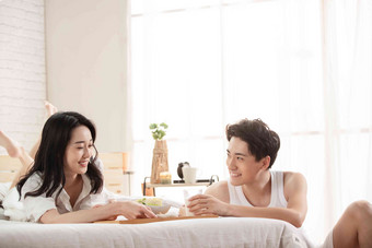 快乐的年轻情侣在床上吃早餐室内清晰摄影图